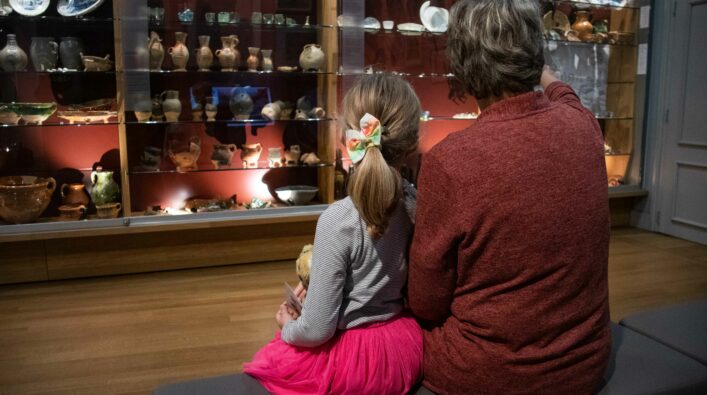 Meisje met vrouwelijk familielid in de Musea Zutphen, zittend en kijkend naar de collectie.